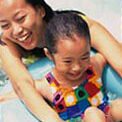 Mother and young daughter enjoying their time in a pool with big smiles and laughter.